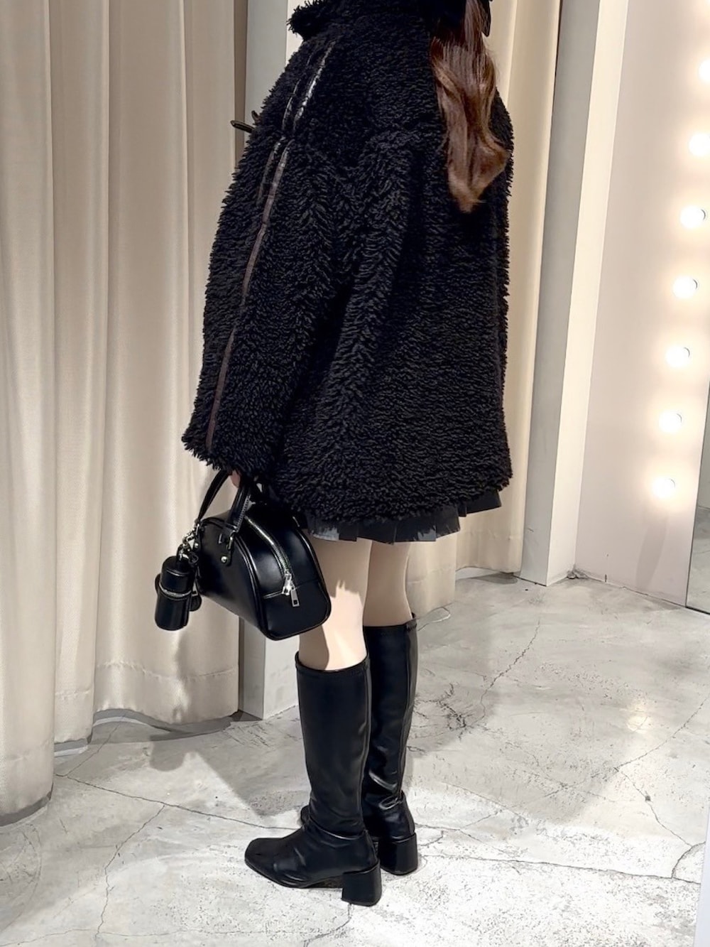 ブラック系のブルゾン、ブラック系のハンドバッグ、グレー系のスカートを着用したレディースの冬コーディネートの7枚目の写真