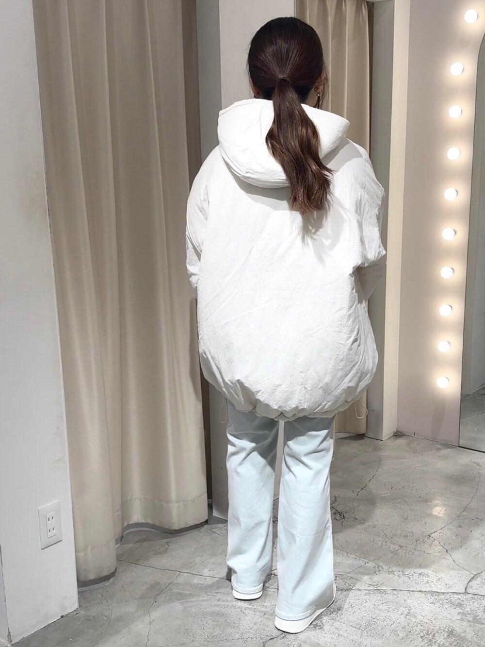 ホワイト系のブルゾン、ホワイト系のハンドバッグ、ブルー系のデニムパンツを着用したレディースの冬コーディネートの4枚目の写真