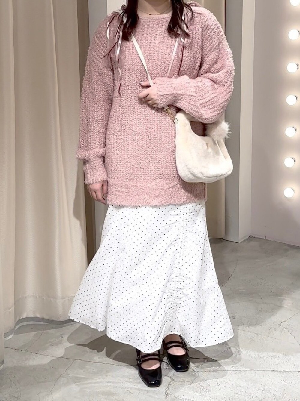 ピンク系のニット/セーター、ホワイト系のハンドバッグ、ホワイト系のスカートを着用したレディースの冬コーディネートの5枚目の写真