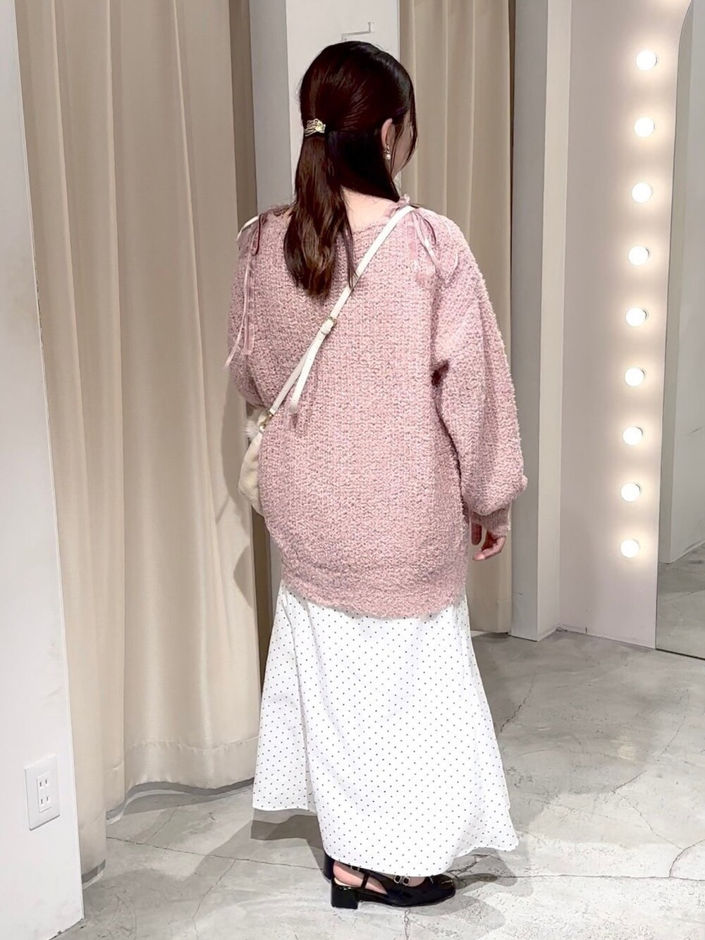 ピンク系のニット/セーター、ホワイト系のハンドバッグ、ホワイト系のスカートを着用したレディースの冬コーディネートの2枚目の写真