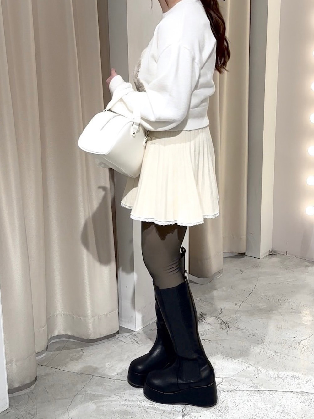 ホワイト系のニット/セーター、ホワイト系のワンピース、ホワイト系のハンドバッグを着用したレディースの冬コーディネートの8枚目の写真