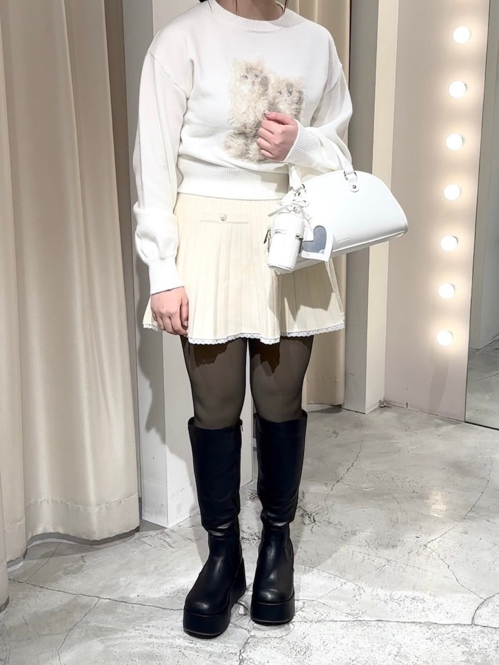 ホワイト系のニット/セーター、ホワイト系のワンピース、ホワイト系のハンドバッグを着用したレディースの冬コーディネートの6枚目の写真