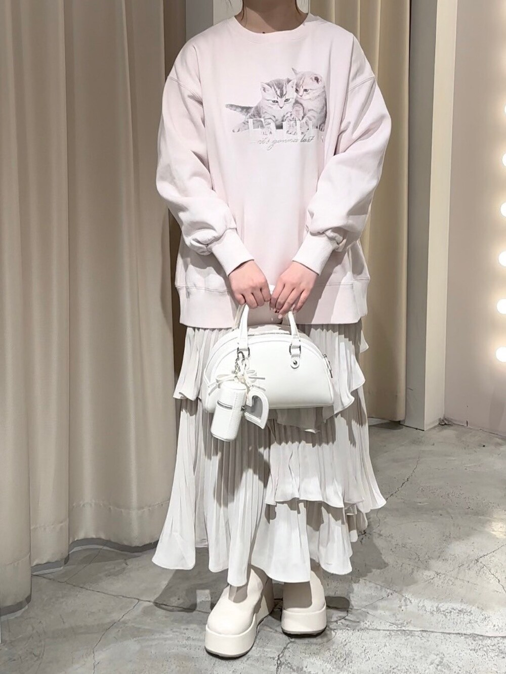 ピンク系のスウェット、ホワイト系のハンドバッグ、ホワイト系のスカートを着用したレディースの冬コーディネートの3枚目の写真