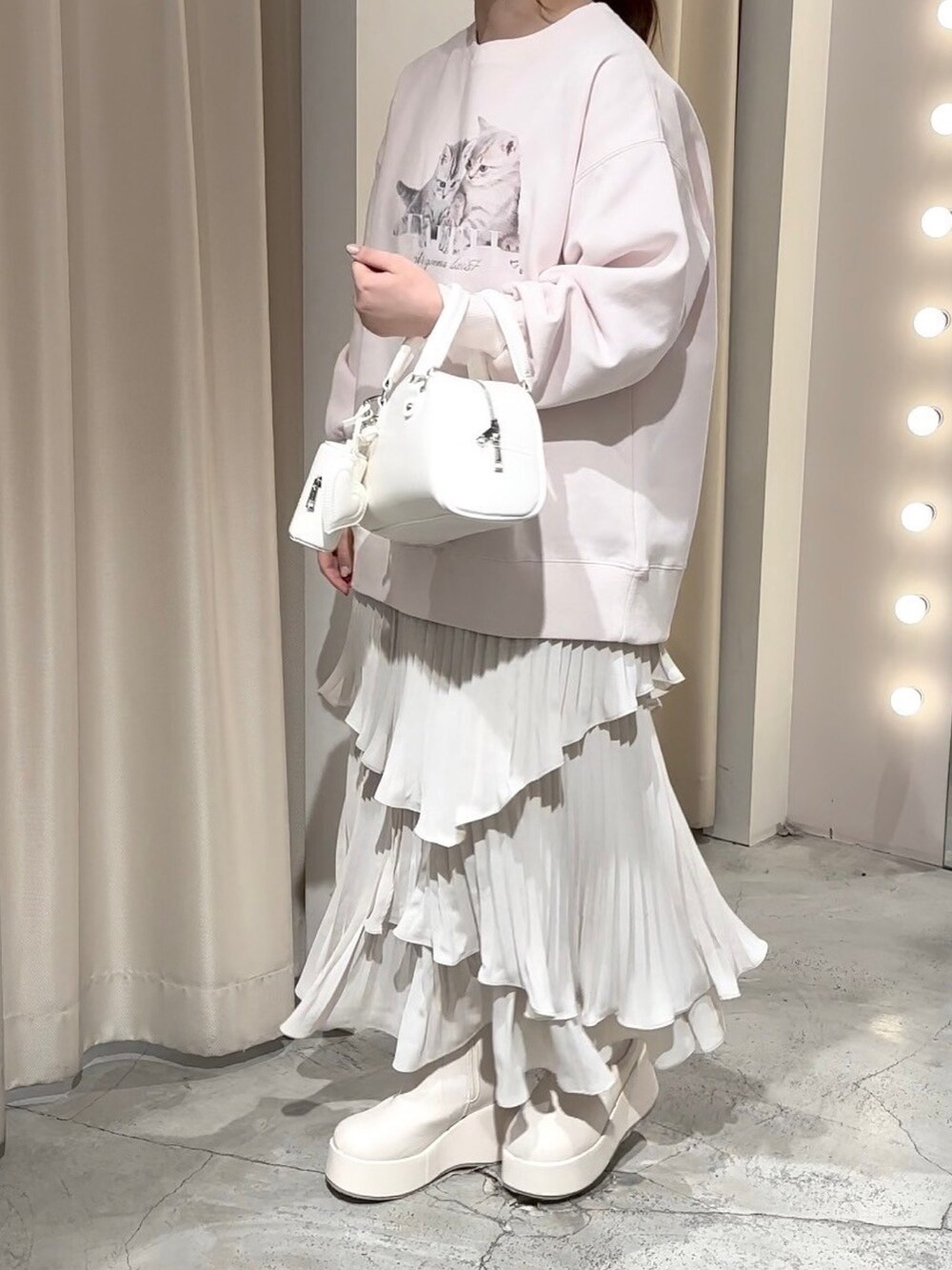 ピンク系のスウェット、ホワイト系のハンドバッグ、ホワイト系のスカートを着用したレディースの冬コーディネートの7枚目の写真