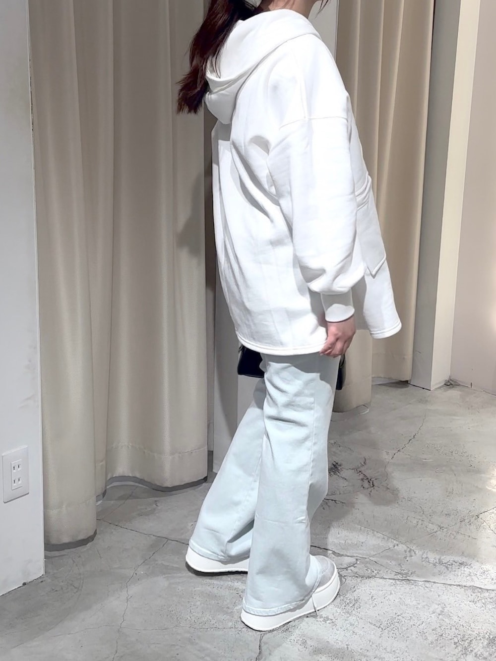 ホワイト系のパーカー、ブラック系のハンドバッグ、ブルー系のデニムパンツを着用したレディースの冬コーディネートの7枚目の写真