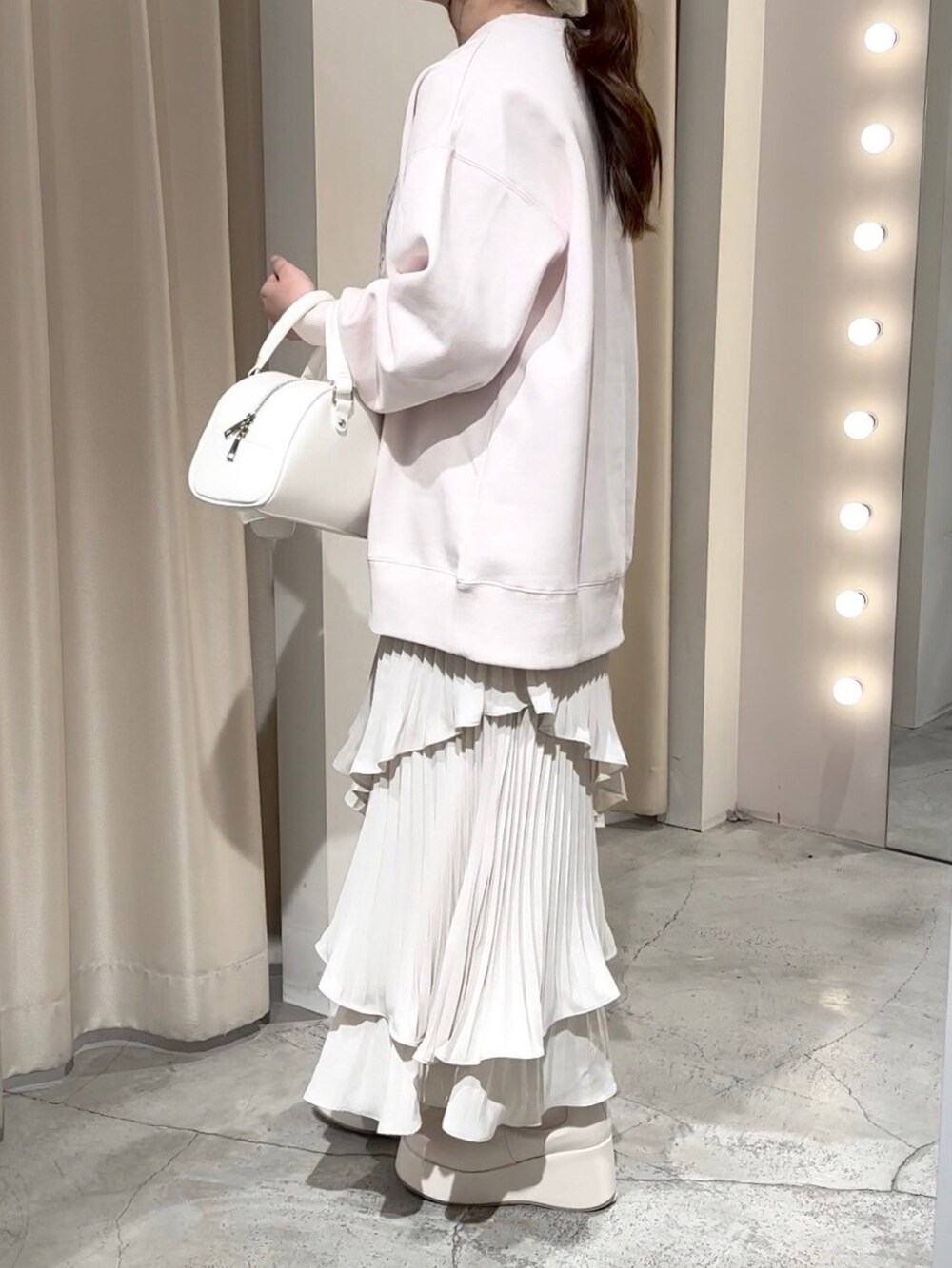 ピンク系のスウェット、ホワイト系のハンドバッグ、ホワイト系のスカートを着用したレディースの冬コーディネートの8枚目の写真