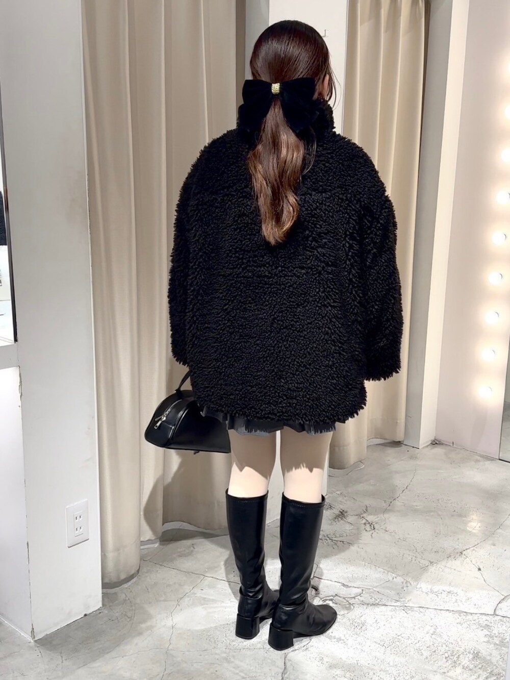 ブラック系のブルゾン、ブラック系のハンドバッグ、グレー系のスカートを着用したレディースの冬コーディネートの4枚目の写真