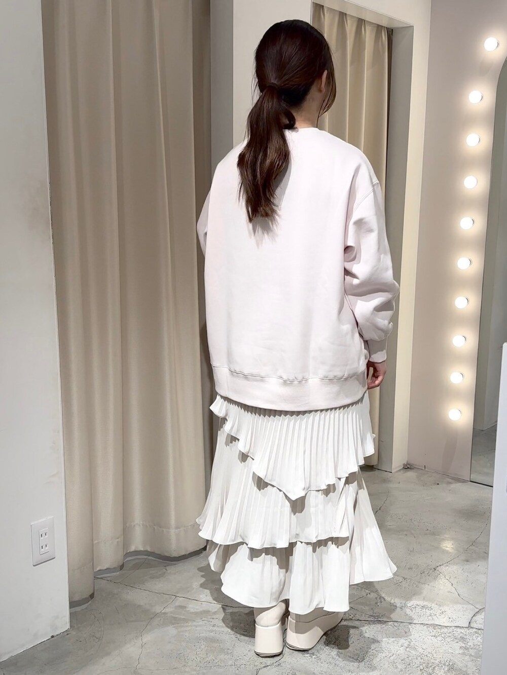 ピンク系のスウェット、ホワイト系のハンドバッグ、ホワイト系のスカートを着用したレディースの冬コーディネートの6枚目の写真
