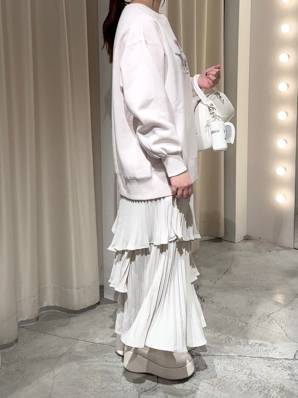 ピンク系のスウェット、ホワイト系のハンドバッグ、ホワイト系のスカートを着用したレディースの冬コーディネートの4枚目の写真