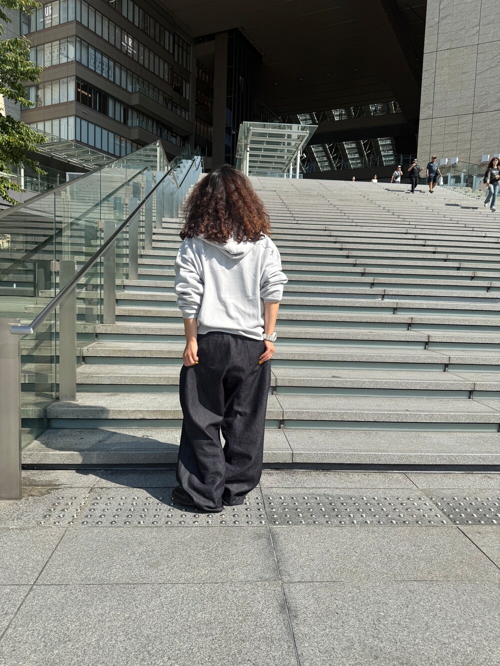 グレー系のパーカー、ブルー系のデニムパンツを着用したレディースの夏コーディネートの4枚目の写真