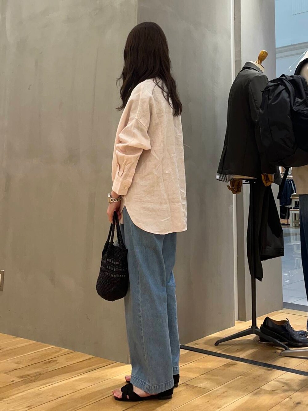 ブルー系のデニムパンツ、ブラック系のショルダーバッグ、ピンク系のシャツ/ブラウスを着用したレディースの春コーディネートの2枚目の写真