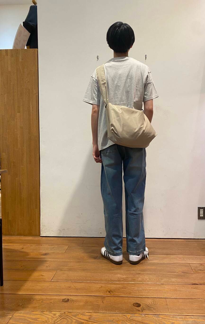 ブルー系のデニムパンツ、ベージュ系のショルダーバッグ、ホワイト系のスニーカーを着用したメンズの夏コーディネートの3枚目の写真