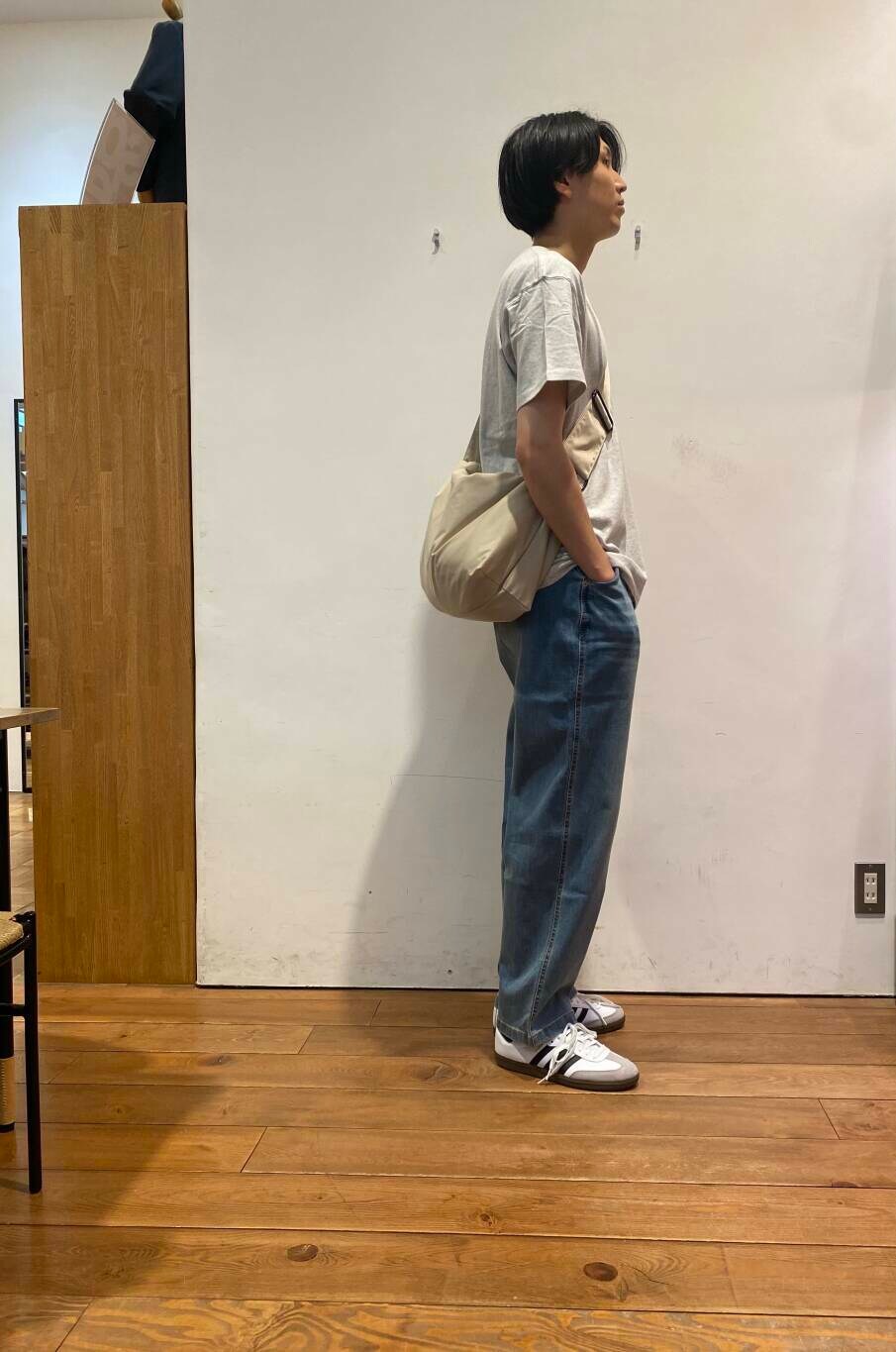 ブルー系のデニムパンツ、ベージュ系のショルダーバッグ、ホワイト系のスニーカーを着用したメンズの夏コーディネートの2枚目の写真