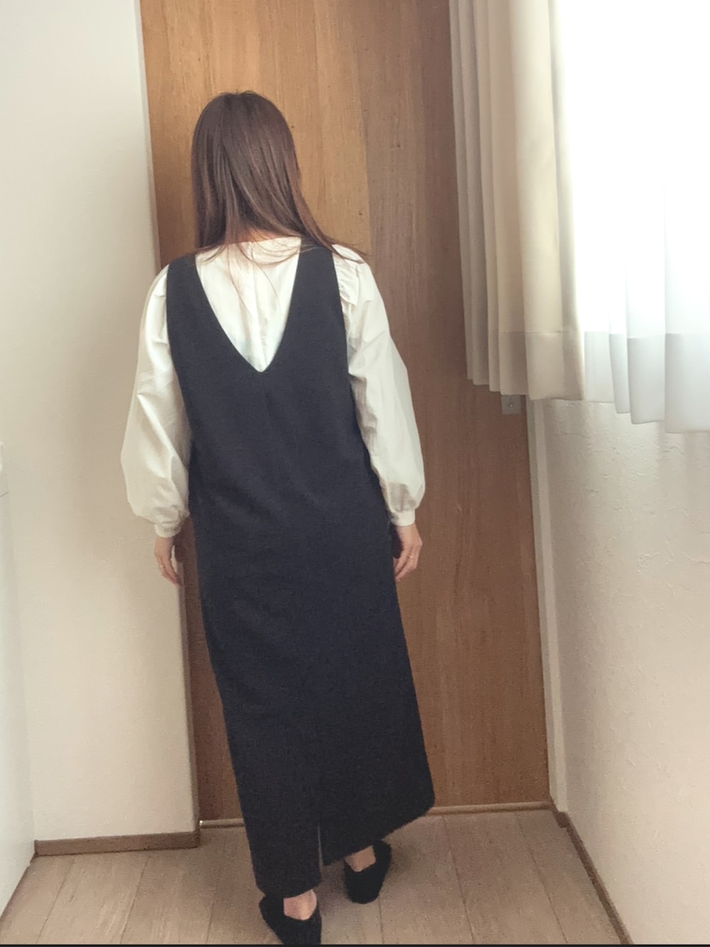 ブラック系のジャンパースカート、ホワイト系のシャツ/ブラウスを着用したレディースの冬コーディネートの2枚目の写真