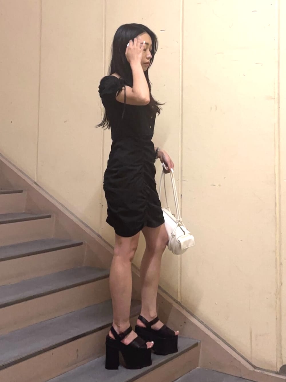 ホワイト系のハンドバッグ、ブラック系のワンピース、ブラック系のサンダルを着用したレディースの夏コーディネートの3枚目の写真