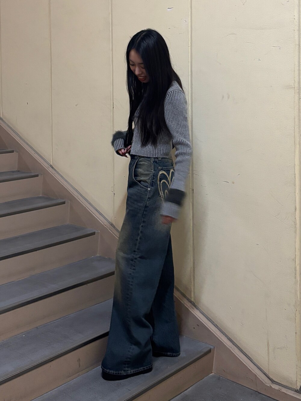 ブルー系のデニムパンツ、グレー系のニット/セーター、ブラック系のブーツを着用したレディースの冬コーディネートの2枚目の写真