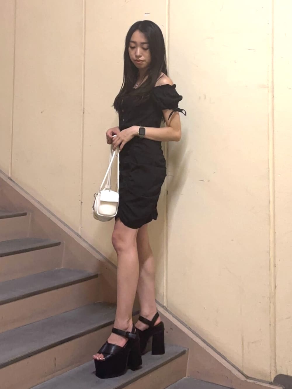 ホワイト系のハンドバッグ、ブラック系のワンピース、ブラック系のサンダルを着用したレディースの夏コーディネートの2枚目の写真