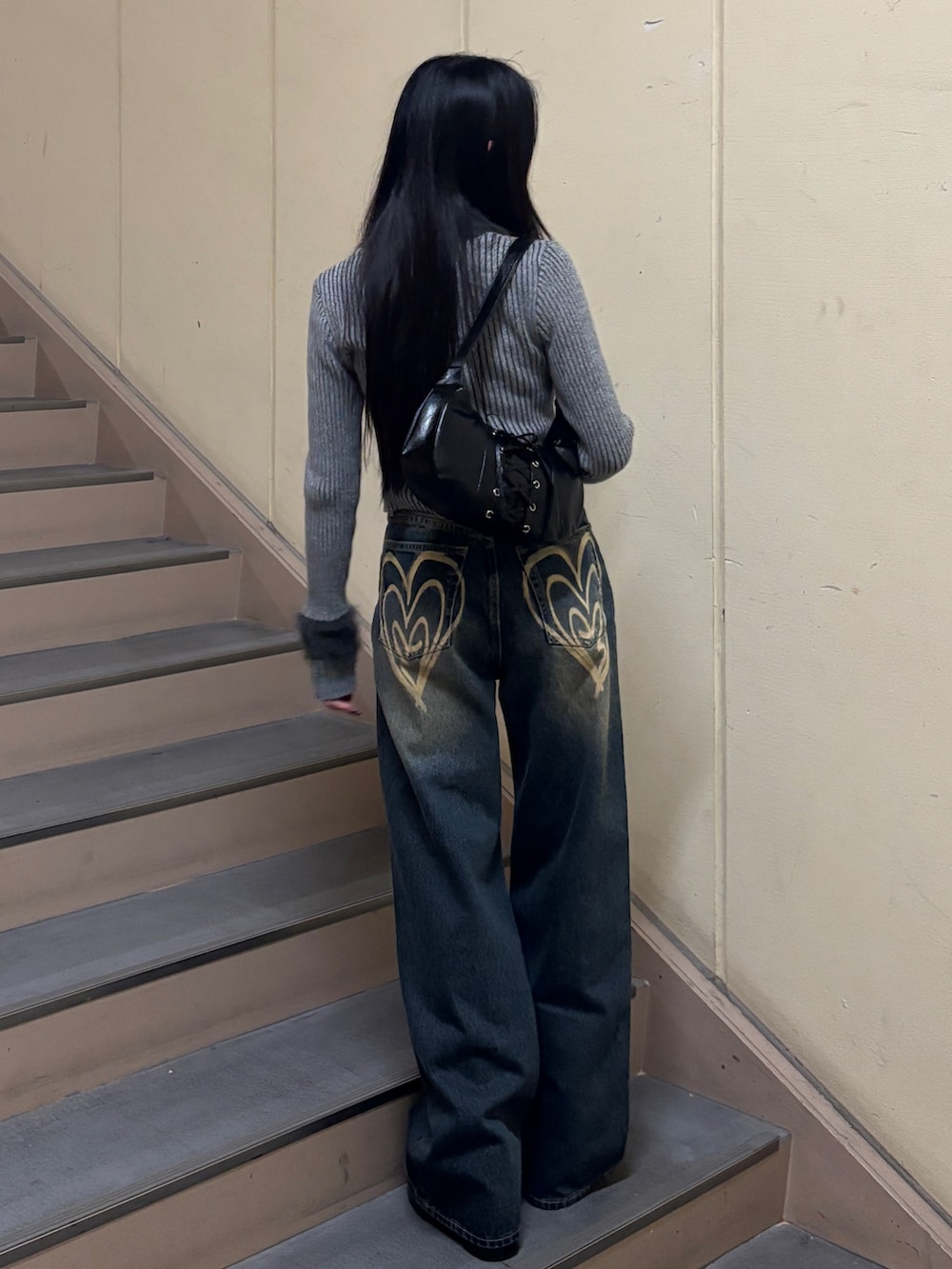 ブルー系のデニムパンツ、グレー系のニット/セーター、ブラック系のブーツを着用したレディースの冬コーディネートの3枚目の写真