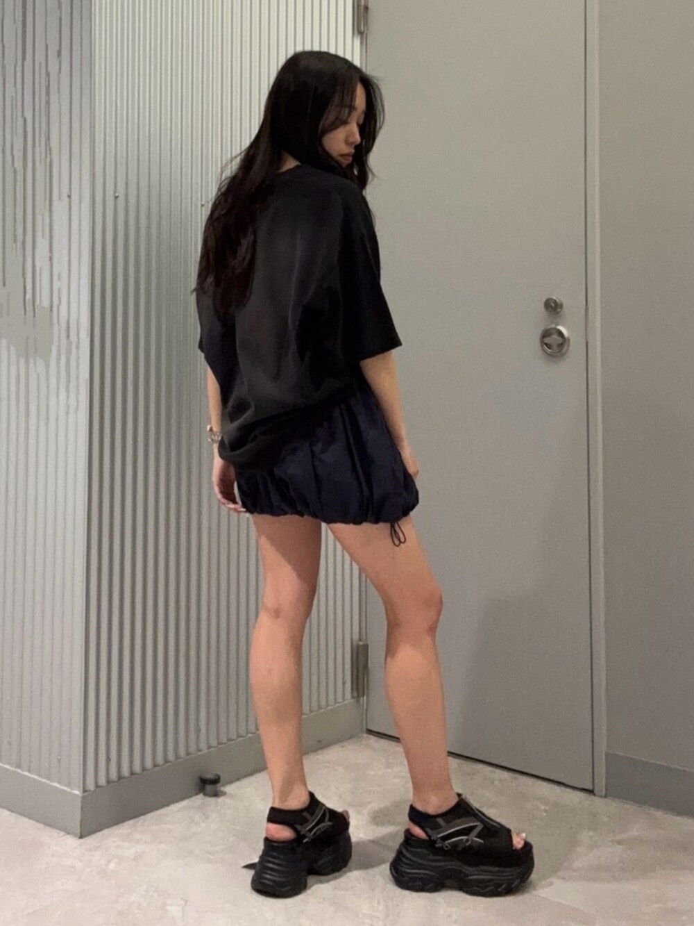 ブラック系のTシャツ/カットソー、ブルー系のスカート、ブラック系のサンダルを着用したレディースの春コーディネートの3枚目の写真