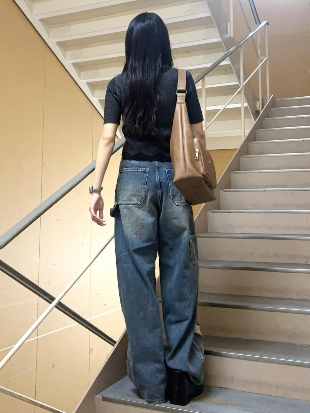 ブルー系のデニムパンツ、ブラック系のニット/セーター、ブラック系のサンダルを着用したレディースの夏コーディネートの3枚目の写真