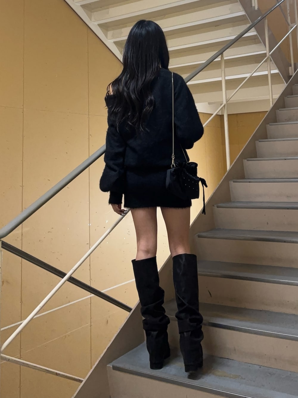 ブラック系のワンピース、ブラック系のブーツ、ブラック系のハンドバッグを着用したレディースの冬コーディネートの4枚目の写真