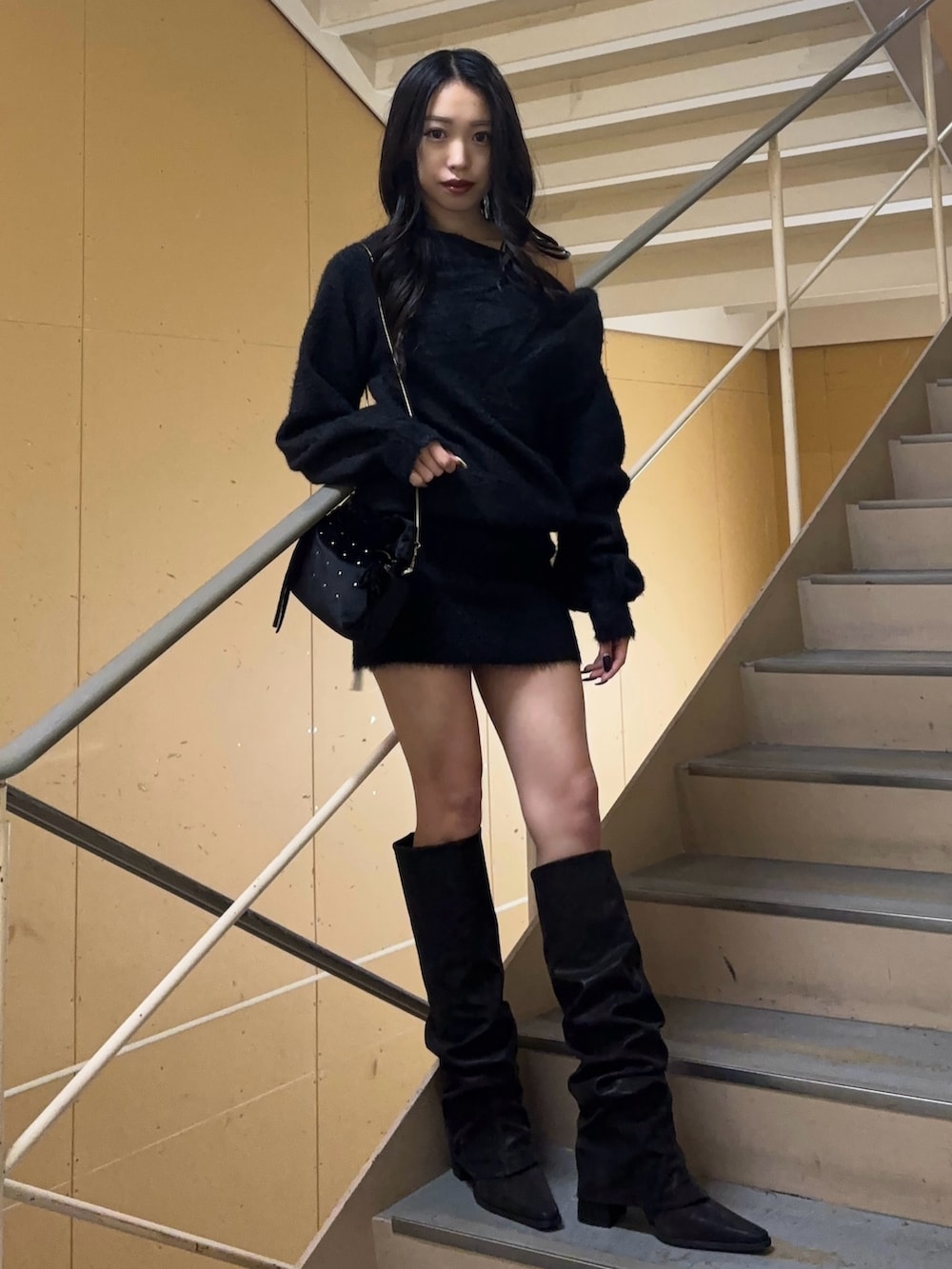 ブラック系のワンピース、ブラック系のブーツ、ブラック系のハンドバッグを着用したレディースの冬コーディネートの2枚目の写真