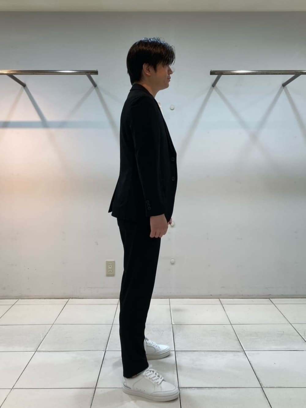 ブラック系のテーラードジャケット、ブラック系のスラックス、ホワイト系のサンダルを着用したメンズの冬コーディネートの4枚目の写真