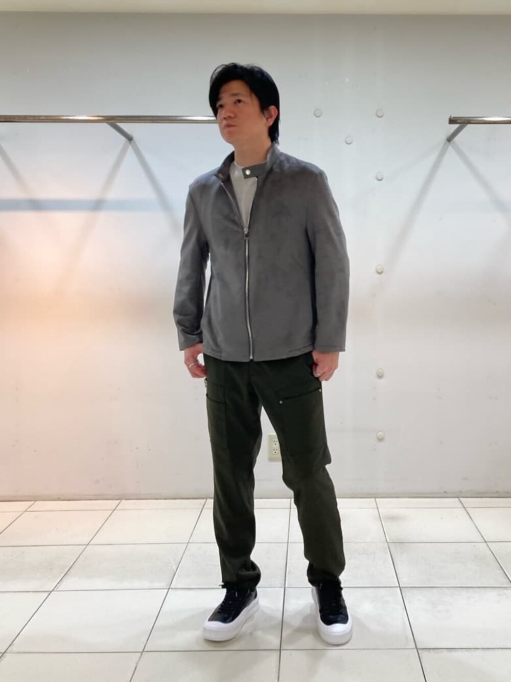 ブラック系のスニーカー、グレー系のライダースジャケット、グリーン系のその他パンツを着用したメンズの春コーディネートの3枚目の写真