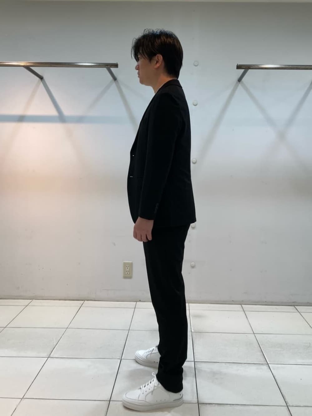 ブラック系のテーラードジャケット、ブラック系のスラックス、ホワイト系のサンダルを着用したメンズの冬コーディネートの3枚目の写真