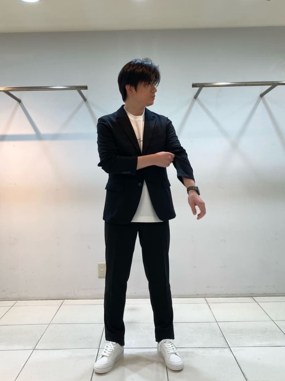 ブラック系のテーラードジャケット、ブラック系のスラックス、ホワイト系のサンダルを着用したメンズの冬コーディネートの2枚目の写真