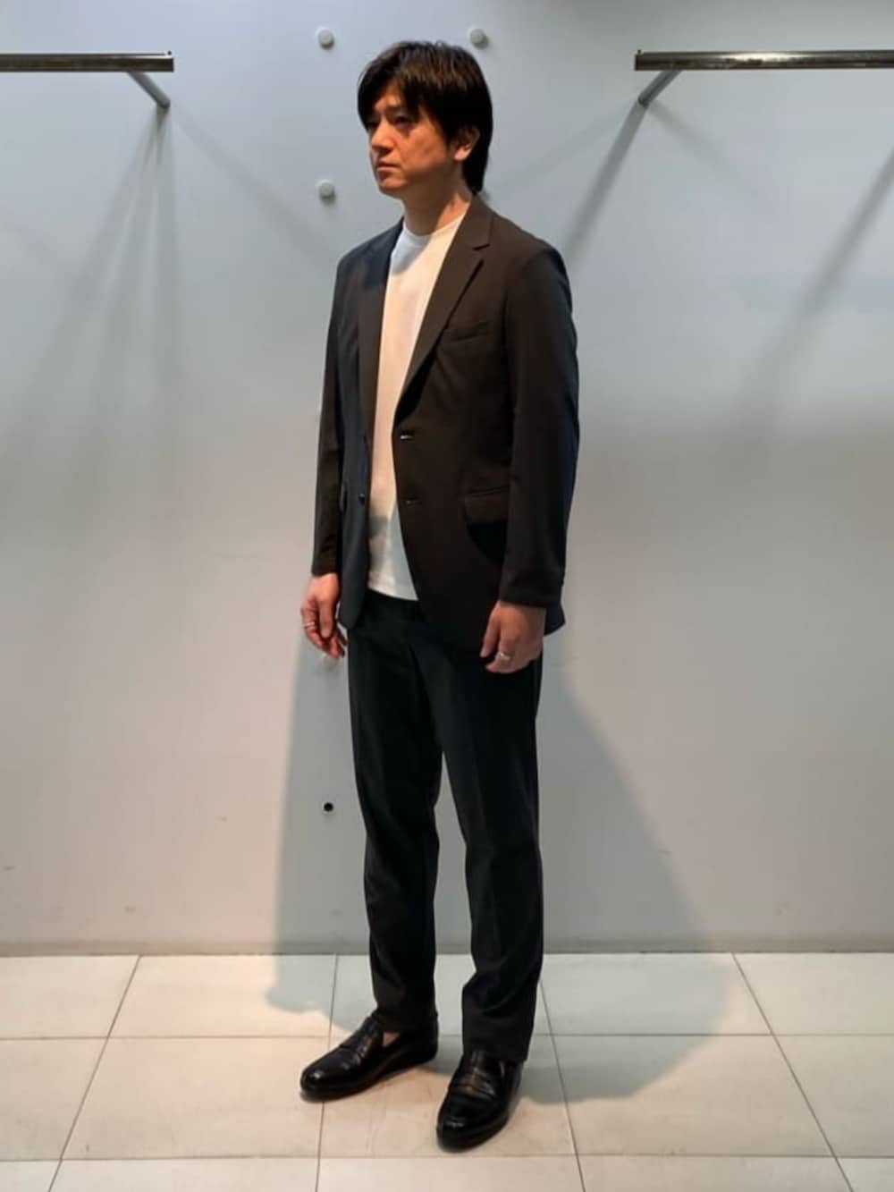 グレー系のテーラードジャケット、グレー系のスラックス、ホワイト系のTシャツ/カットソーを着用したメンズの春コーディネートの4枚目の写真