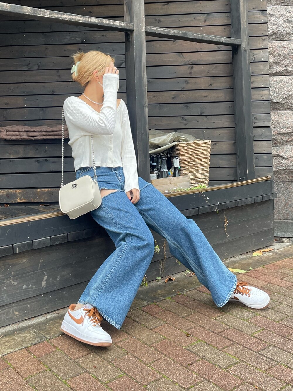 ブルー系のデニムパンツ、ホワイト系のショルダーバッグ、ホワイト系のトップスを着用したレディースの秋コーディネートの2枚目の写真