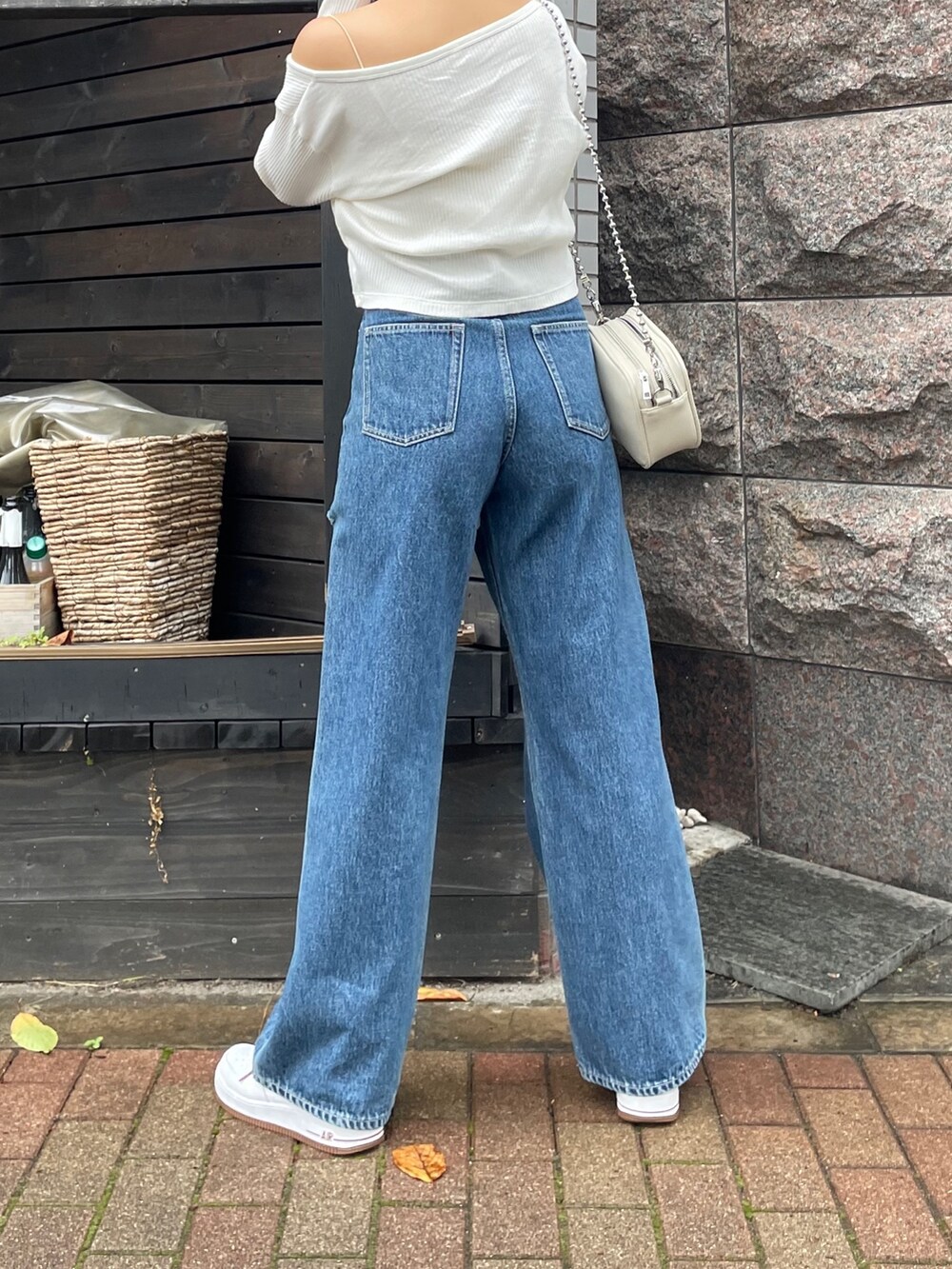 ブルー系のデニムパンツ、ホワイト系のショルダーバッグ、ホワイト系のトップスを着用したレディースの秋コーディネートの3枚目の写真