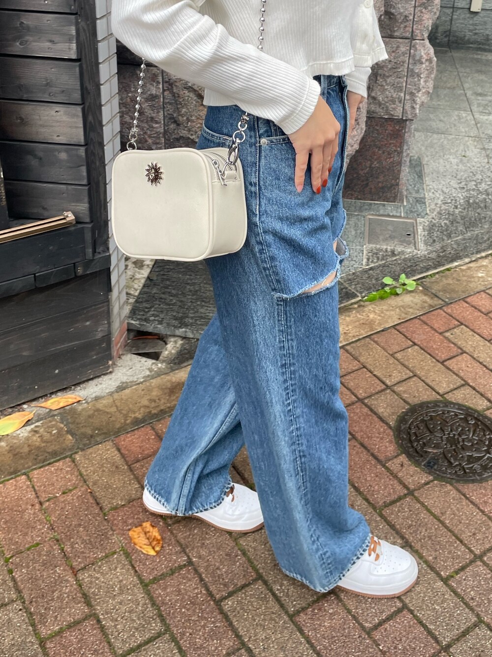 ブルー系のデニムパンツ、ホワイト系のショルダーバッグ、ホワイト系のトップスを着用したレディースの秋コーディネートの5枚目の写真