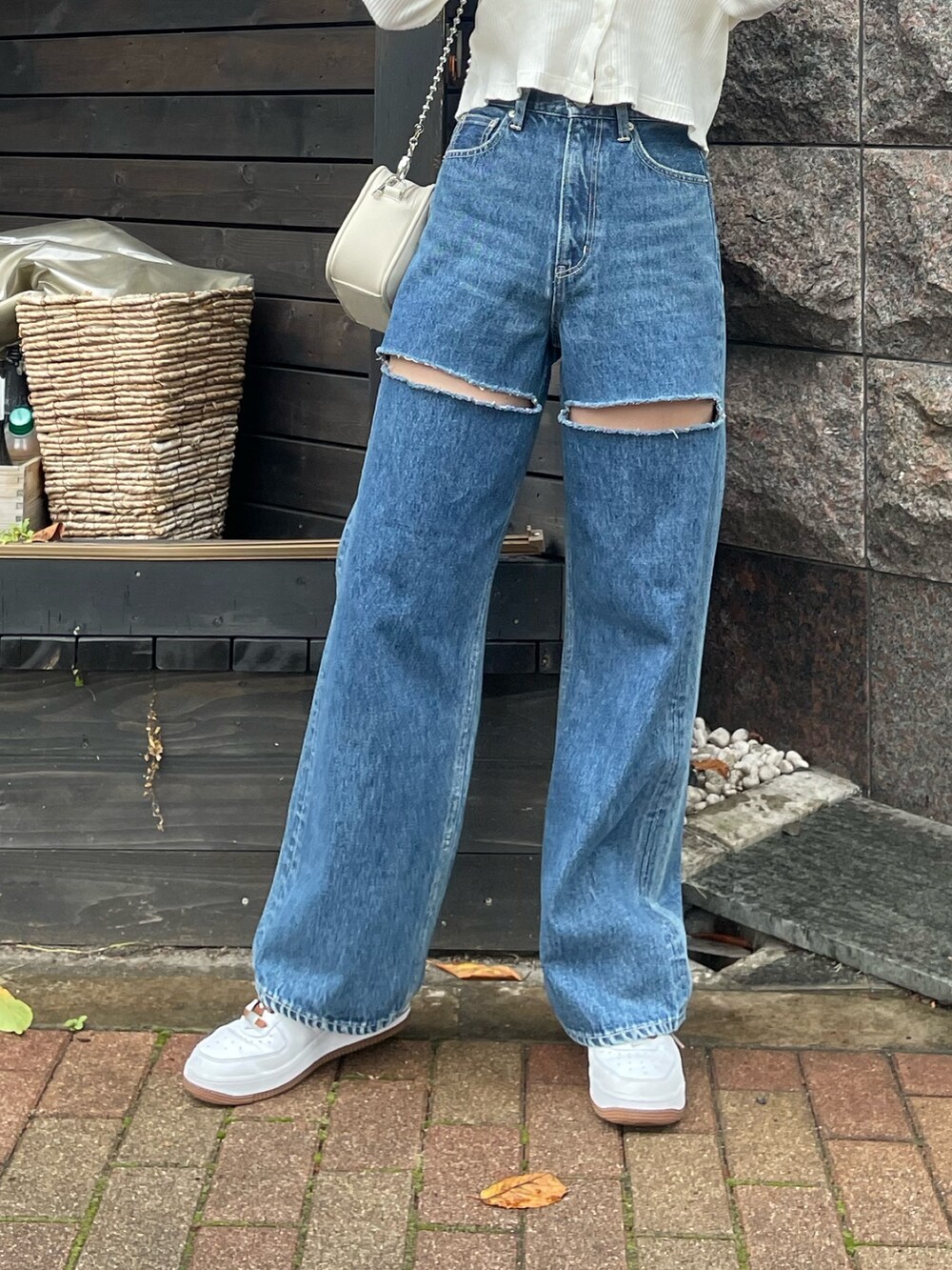 ブルー系のデニムパンツ、ホワイト系のショルダーバッグ、ホワイト系のトップスを着用したレディースの秋コーディネートの4枚目の写真