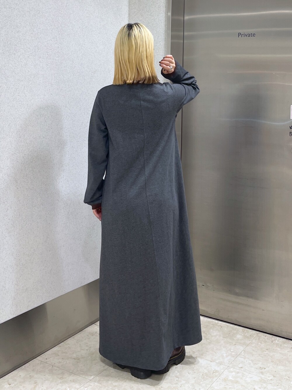 ブラック系のダウンベスト、ブラウン系のボストンバッグ、グレー系のワンピースを着用したレディースの秋コーディネートの9枚目の写真