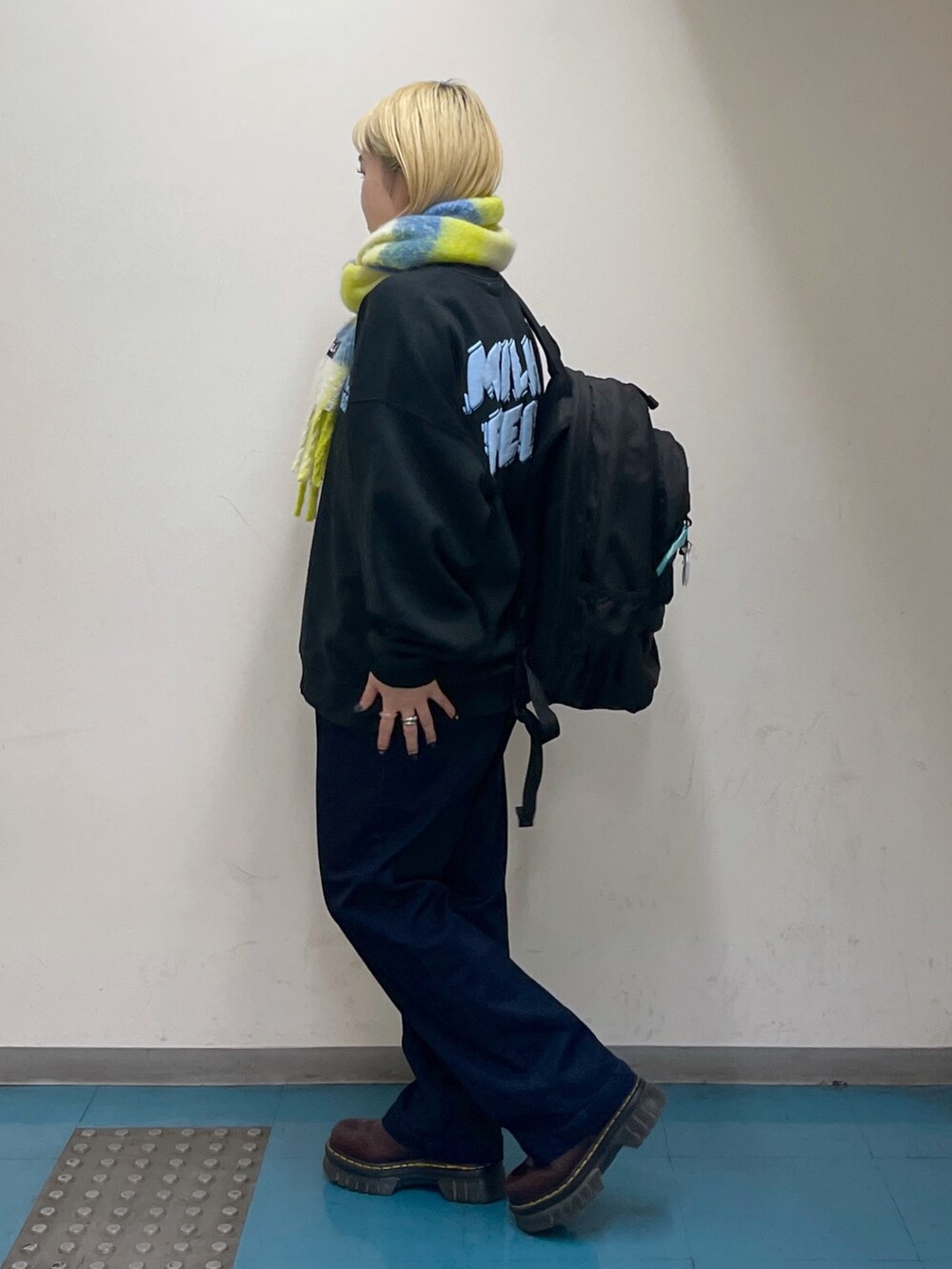 ブルー系のデニムパンツ、グリーン系のバックパック/リュック、ブラック系のスウェットを着用したレディースの秋コーディネートの3枚目の写真