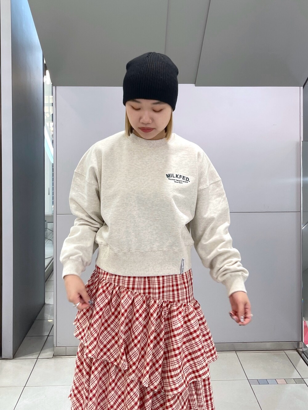 レッド系のスカート、ベージュ系のスウェット、ブラック系のショルダーバッグを着用したレディースの冬コーディネートの6枚目の写真