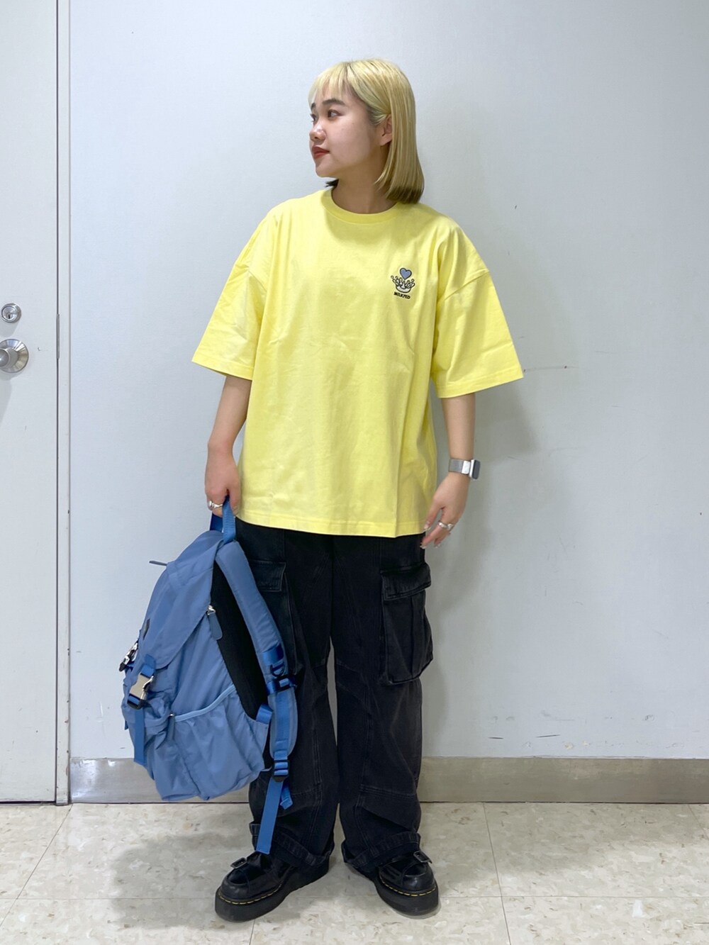 ブラック系のカーゴパンツ、ブルー系のバックパック/リュック、イエロー系のTシャツ/カットソーを着用したレディースの春コーディネートの4枚目の写真