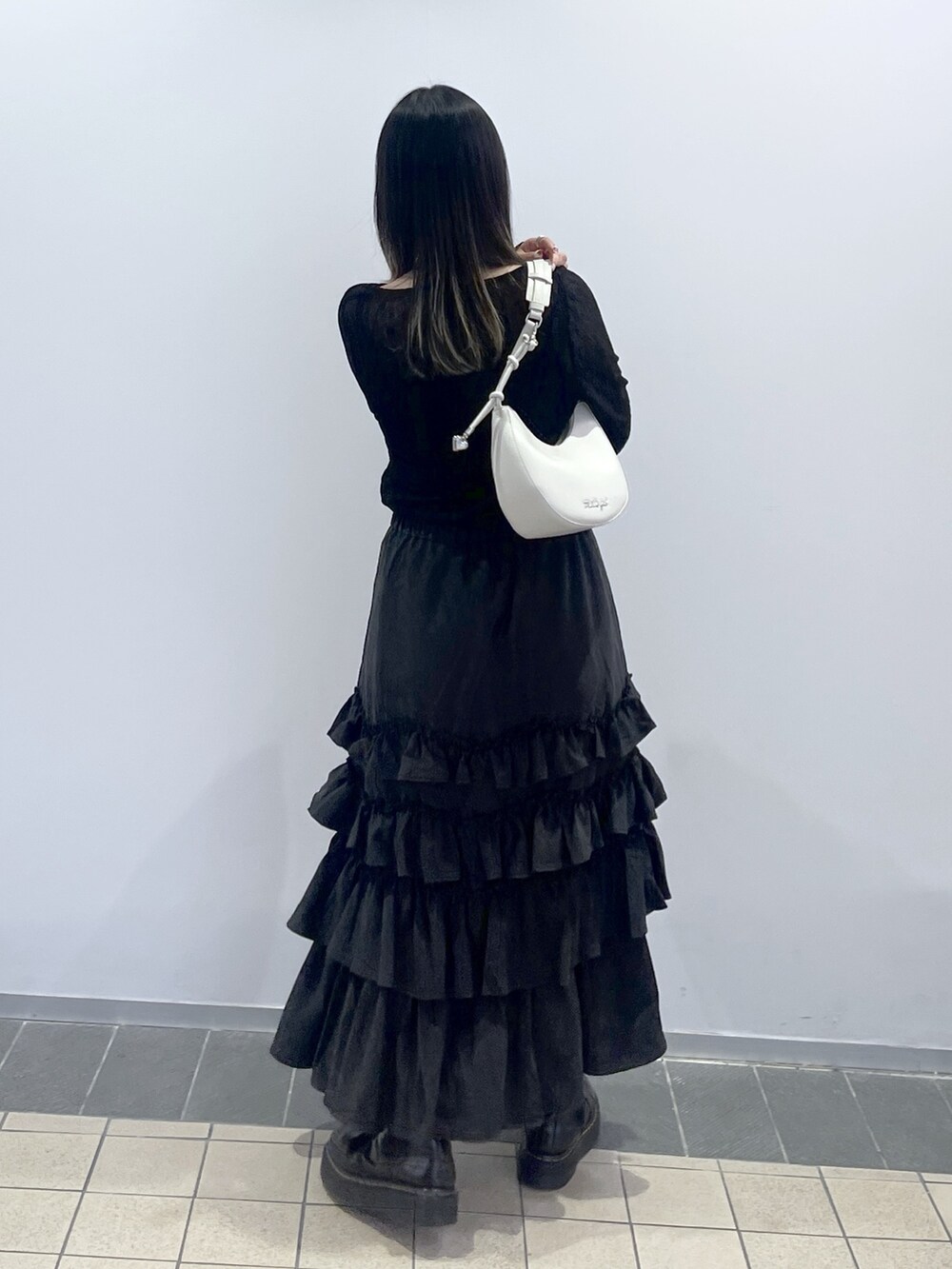 ブラック系のTシャツ/カットソー、ブラック系のスカート、ホワイト系のハンドバッグを着用したレディースの秋コーディネートの5枚目の写真