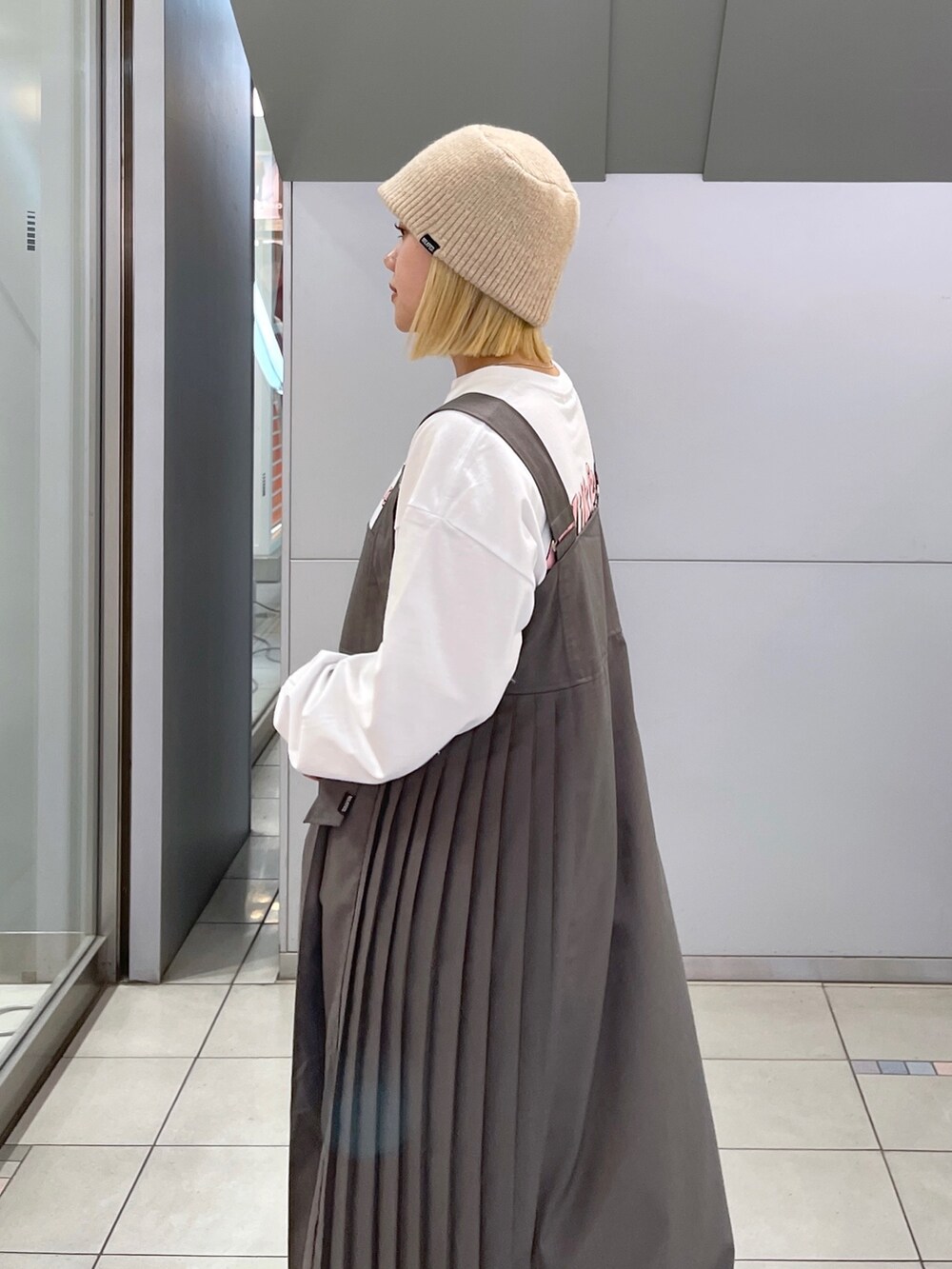 ホワイト系のTシャツ/カットソー、グレー系のジャンパースカート、ブラック系のショルダーバッグを着用したレディースの冬コーディネートの7枚目の写真