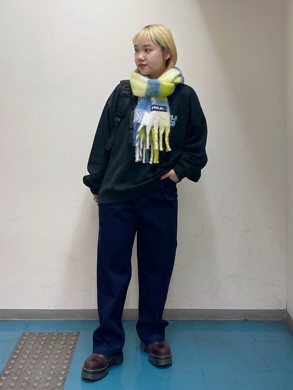 ブルー系のデニムパンツ、グリーン系のバックパック/リュック、ブラック系のスウェットを着用したレディースの秋コーディネートの2枚目の写真