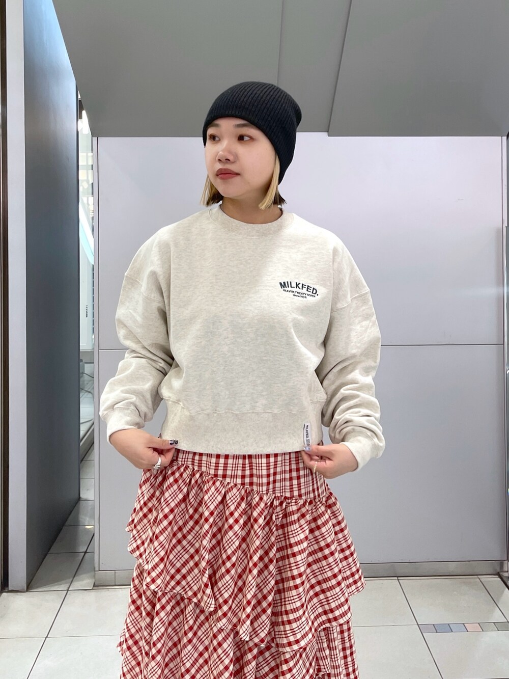 レッド系のスカート、ベージュ系のスウェット、ブラック系のショルダーバッグを着用したレディースの冬コーディネートの5枚目の写真