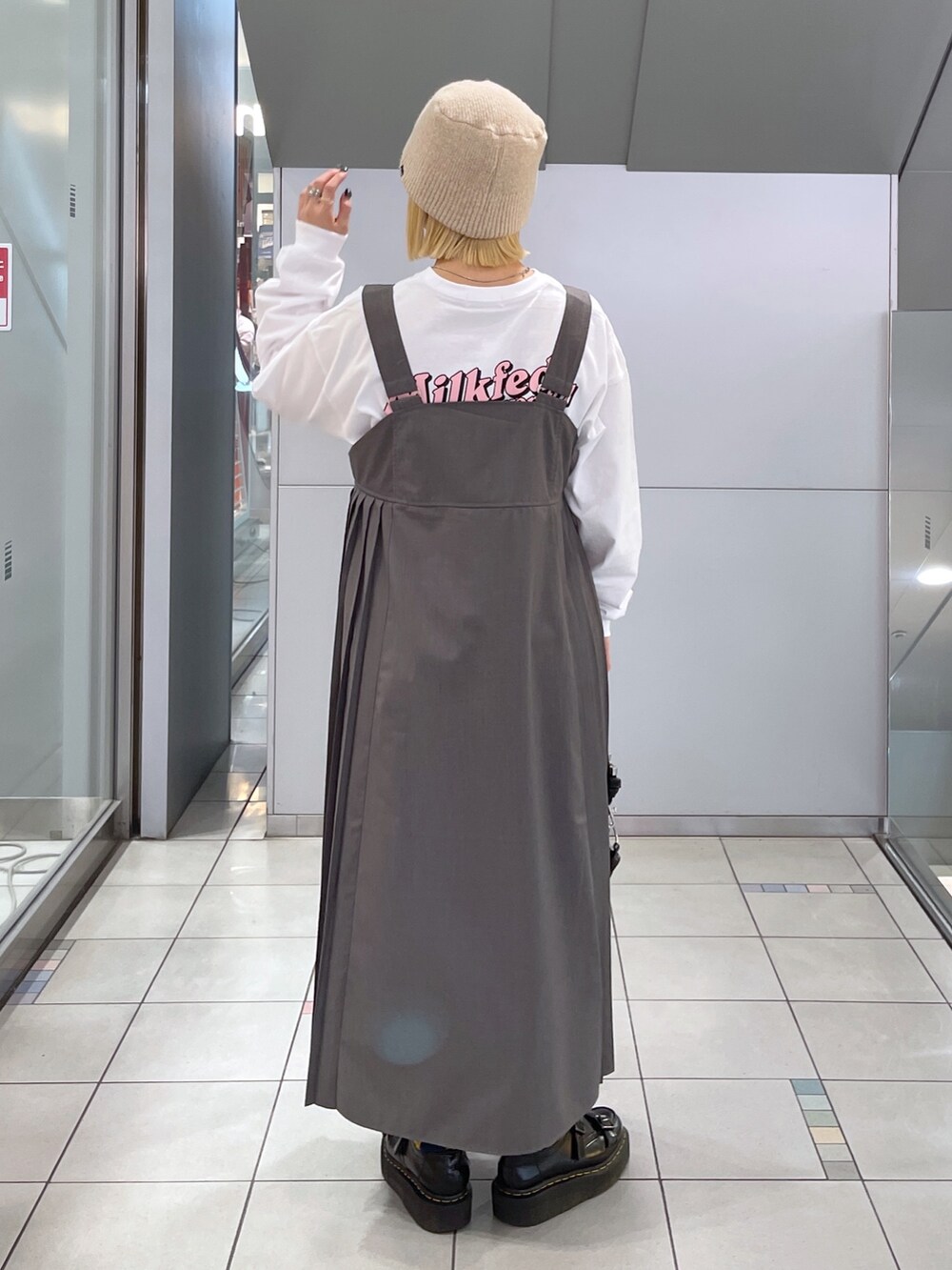 ホワイト系のTシャツ/カットソー、グレー系のジャンパースカート、ブラック系のショルダーバッグを着用したレディースの冬コーディネートの5枚目の写真