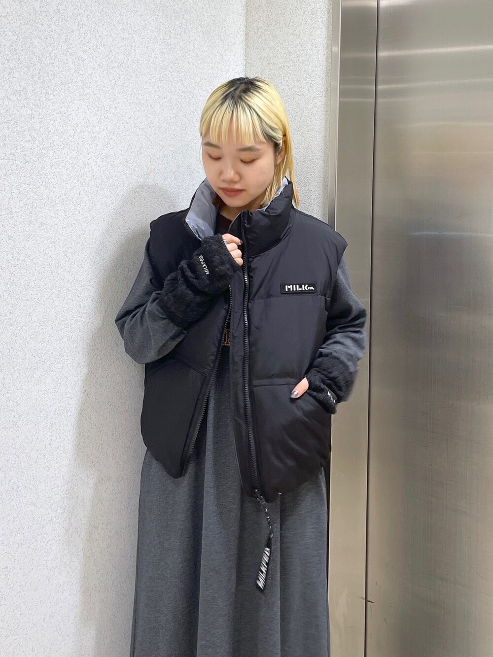 ブラック系のダウンベスト、ブラウン系のボストンバッグ、グレー系のワンピースを着用したレディースの秋コーディネートの5枚目の写真