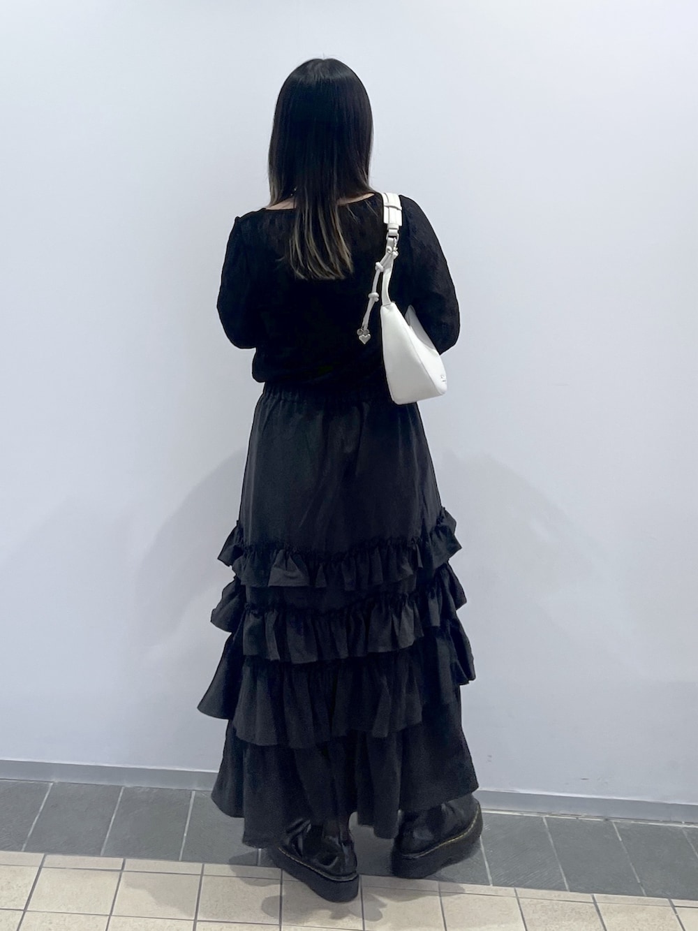 ブラック系のTシャツ/カットソー、ブラック系のスカート、ホワイト系のハンドバッグを着用したレディースの秋コーディネートの6枚目の写真