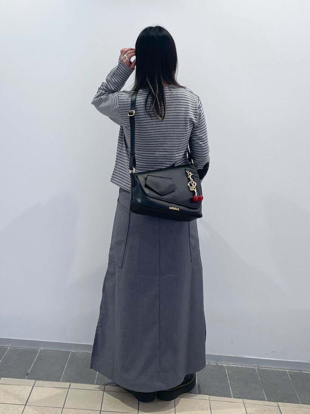 グレー系のスカート、ブラック系のショルダーバッグ、グレー系のカーディガン/ボレロを着用したレディースの秋コーディネートの5枚目の写真