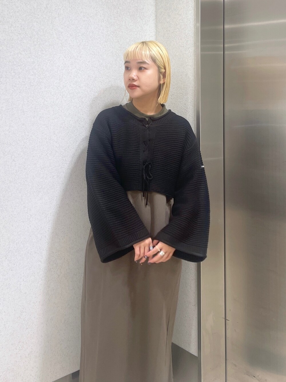 ブラック系のカーディガン/ボレロ、グリーン系のワンピース、ホワイト系のハンドバッグを着用したレディースの秋コーディネートの7枚目の写真