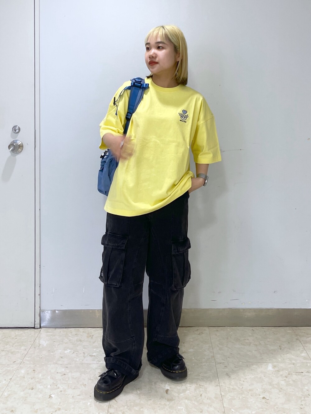 ブラック系のカーゴパンツ、ブルー系のバックパック/リュック、イエロー系のTシャツ/カットソーを着用したレディースの春コーディネートの3枚目の写真