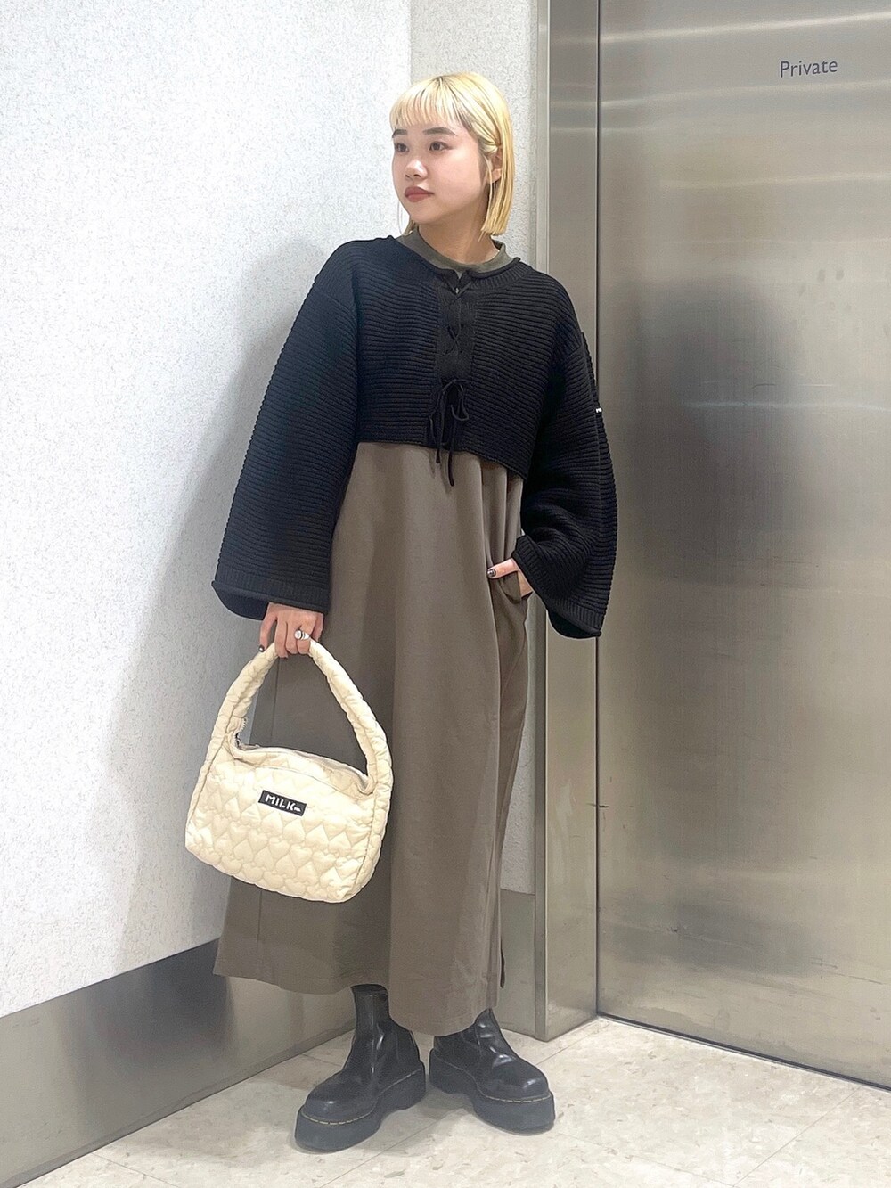 ブラック系のカーディガン/ボレロ、グリーン系のワンピース、ホワイト系のハンドバッグを着用したレディースの秋コーディネートの3枚目の写真